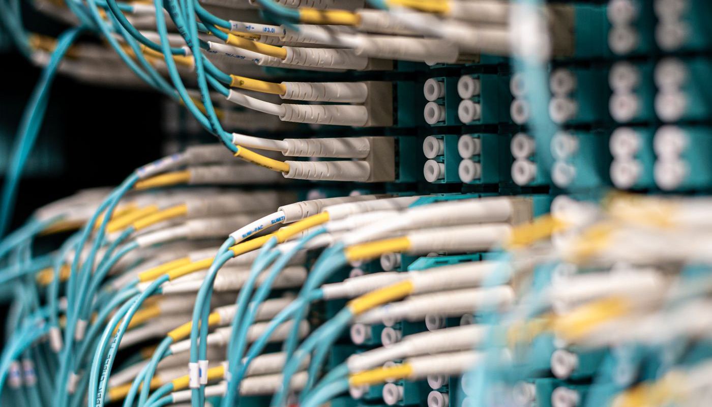 Blue network cables plugged into a patch panel in a server room